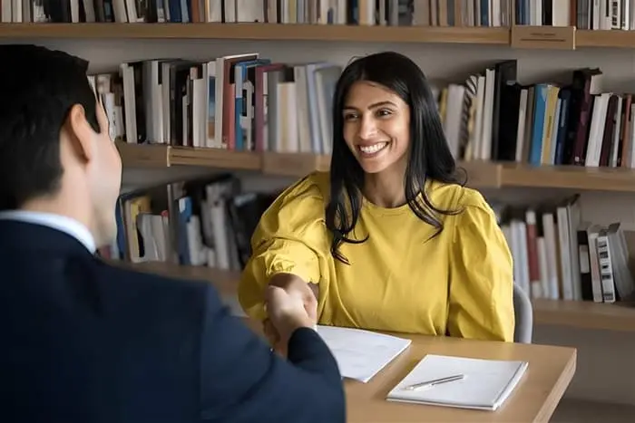 Executive Hiring meeting showing a diverse leadership candidate shaking hands with a recruiter during a senior level interview discussion