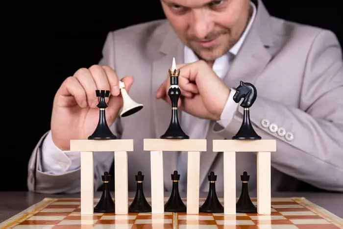 CEO demonstrating key leadership qualities by strategically positioning chess pieces to represent decision making, foresight, and leadership